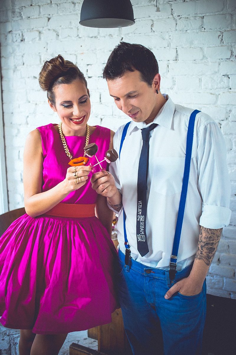 Par zajedno — ona mu pokazuje naočare, on u beloj košulji sa tregerima