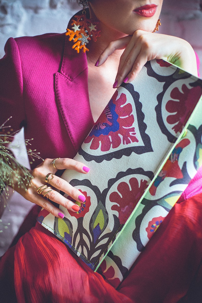 Detalj — folk-print torbica, koralne minđuše i magenta sako