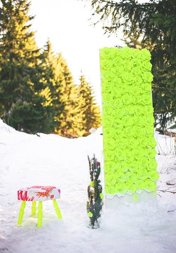 Neon zeleni zid od papirnatih cvetova na snegu sa fluorescentnim tronošcem