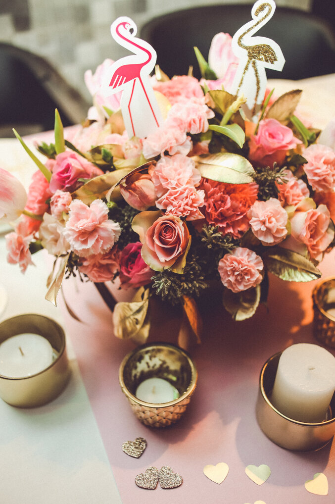 Cvetna dekoracija iz ptičje perspektive na roze stolnjaku sa zlatnim srcima