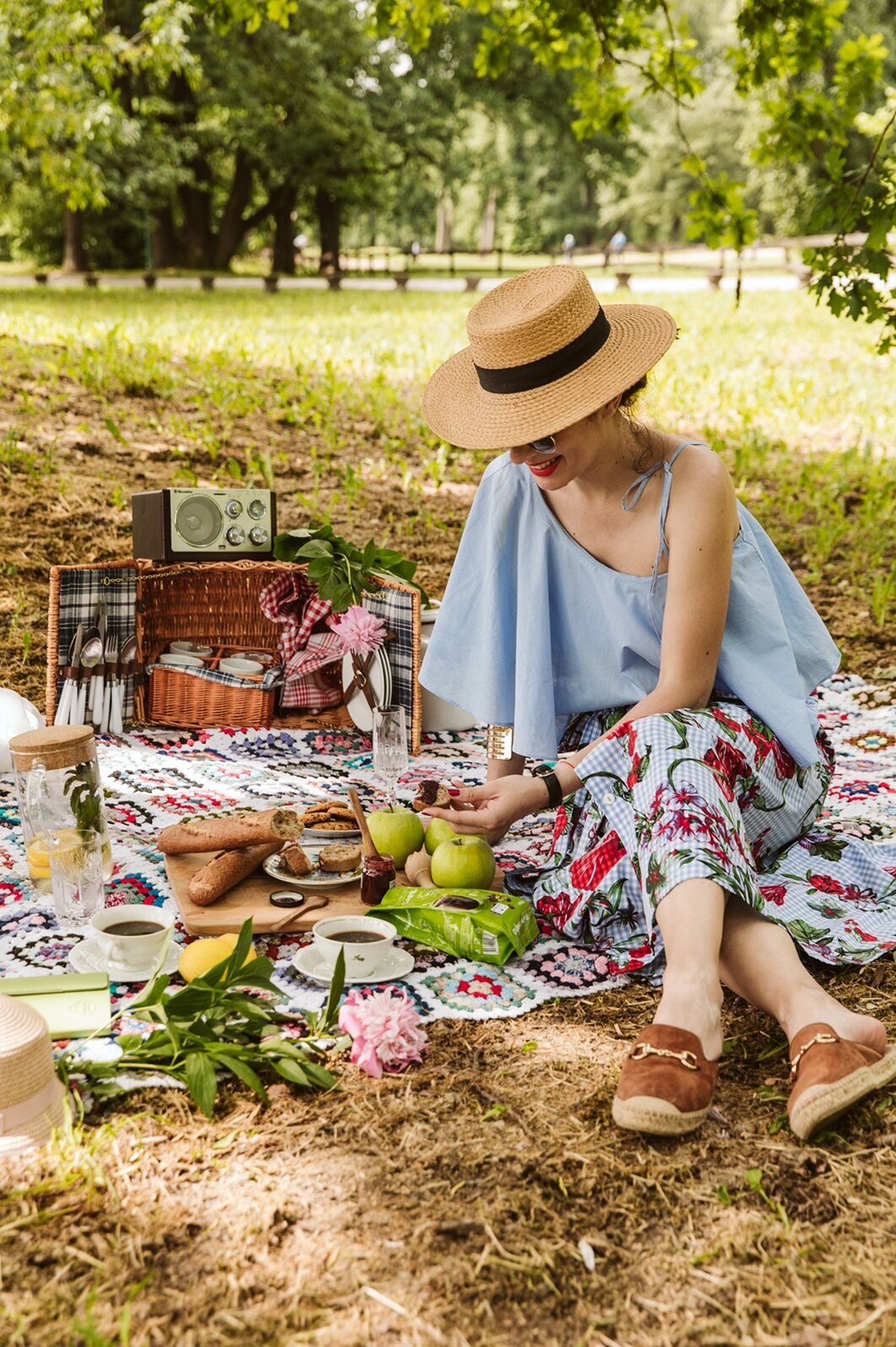 Žena sa slamnim šeširom sedi na pikniku